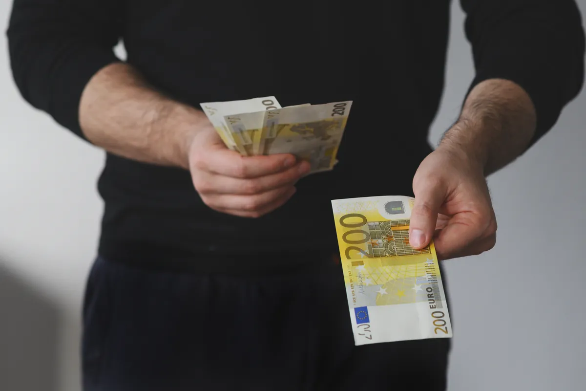 Homme tenant une liasse de billets en euros