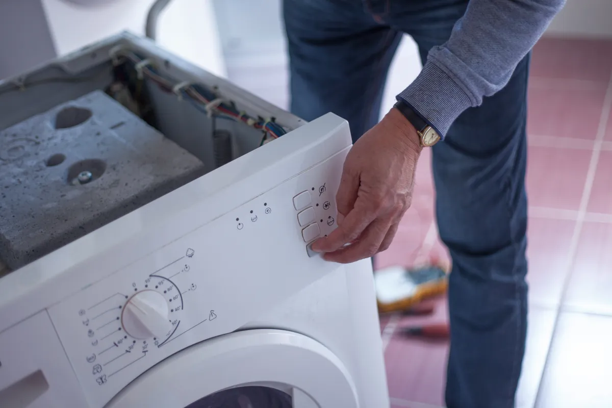 Homme réparant une machine à laver en panne à la maison