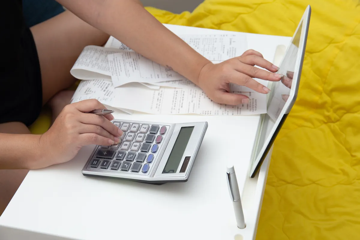 Calcul du budget à la maison avec calculatrice et tablette avant d'emprunter