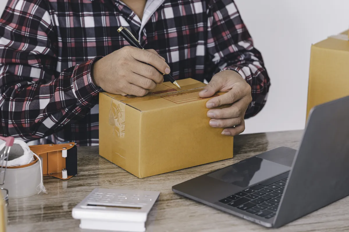 Homme préparant un colis vendu en ligne pour gagner de l'argent
