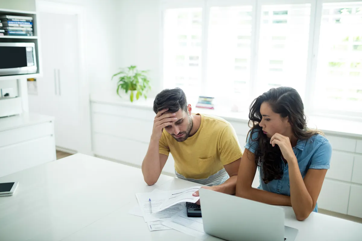 Couple inquiet examinant ses finances à la table de la cuisine