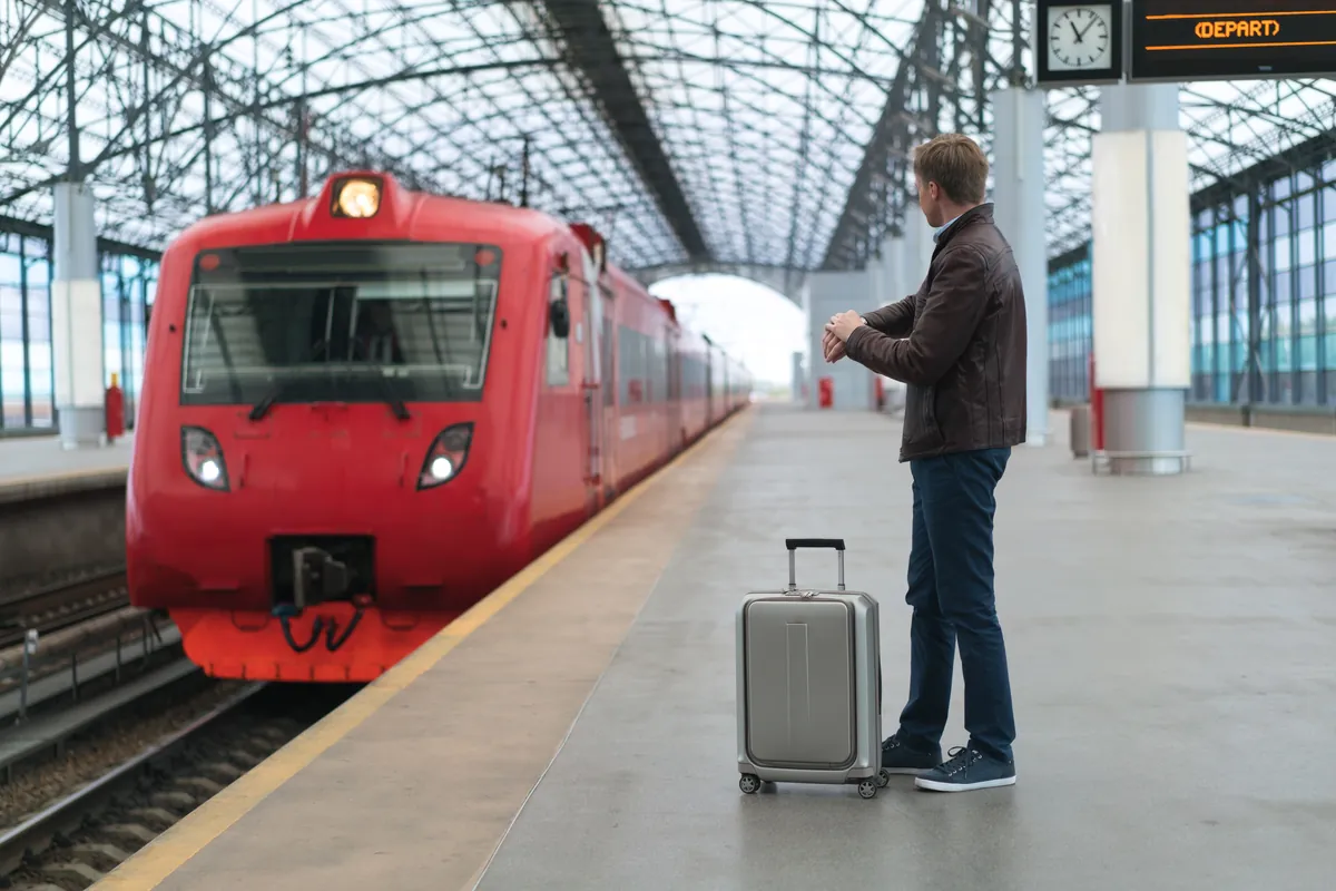 Voyageur avec sa valise attendant le train sur le quai d'une gare