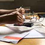 Homme faisant ses comptes avec des factures et une calculatrice