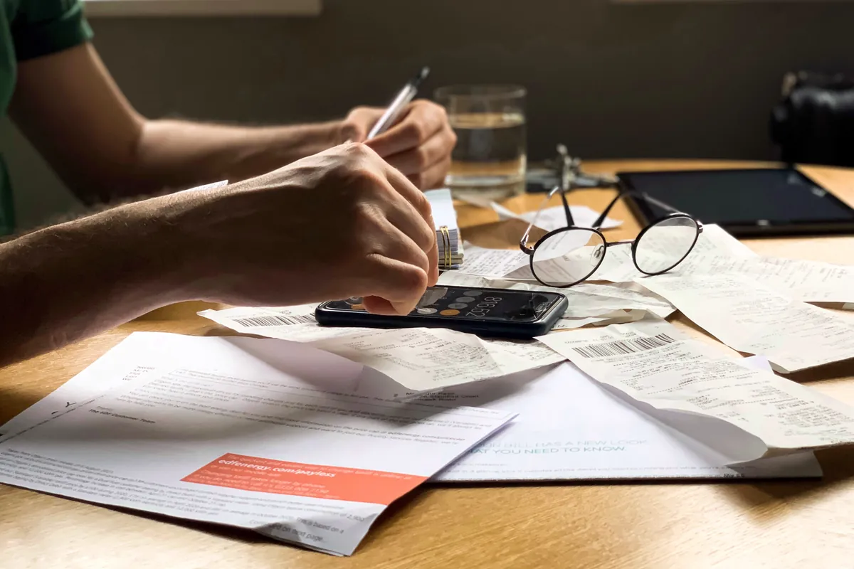 Homme faisant ses comptes avec des factures et une calculatrice