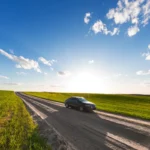 Voiture roulant sur une route de campagne entre des champs verts