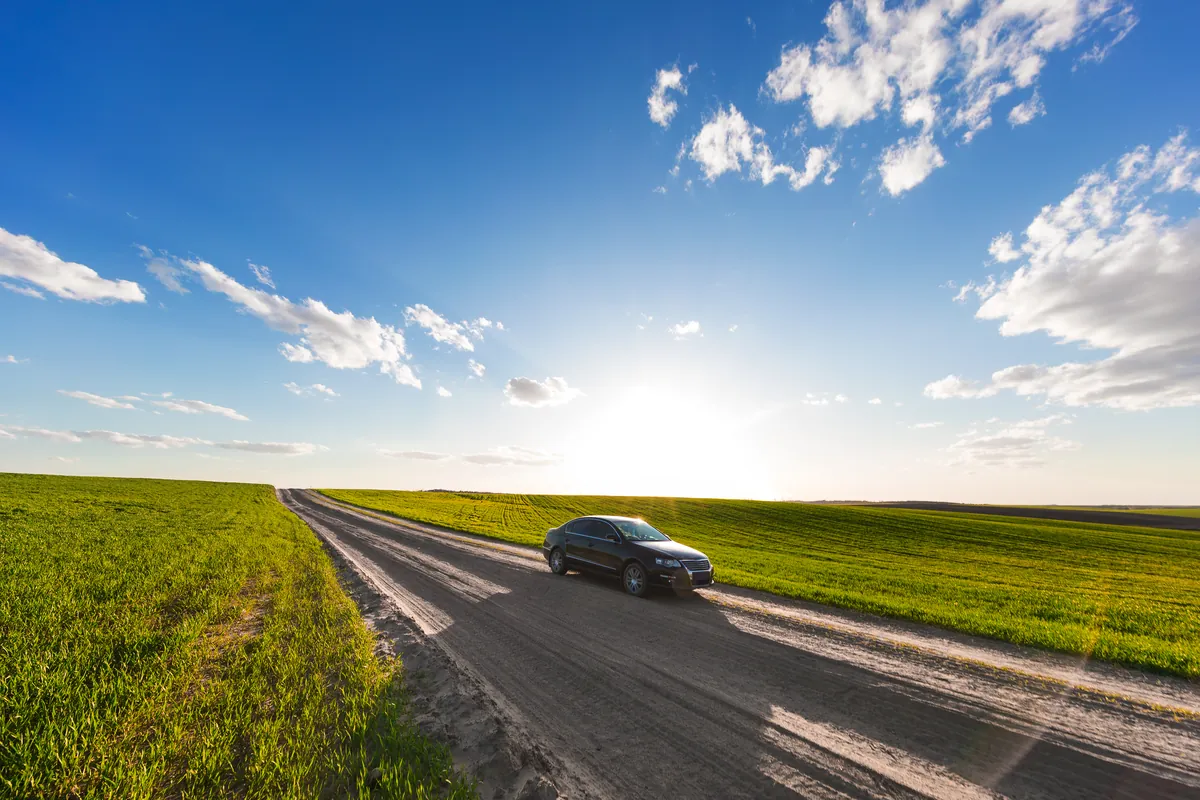 Voiture roulant sur une route de campagne entre des champs verts