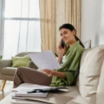 Femme examinant un document chez elle devant son ordinateur