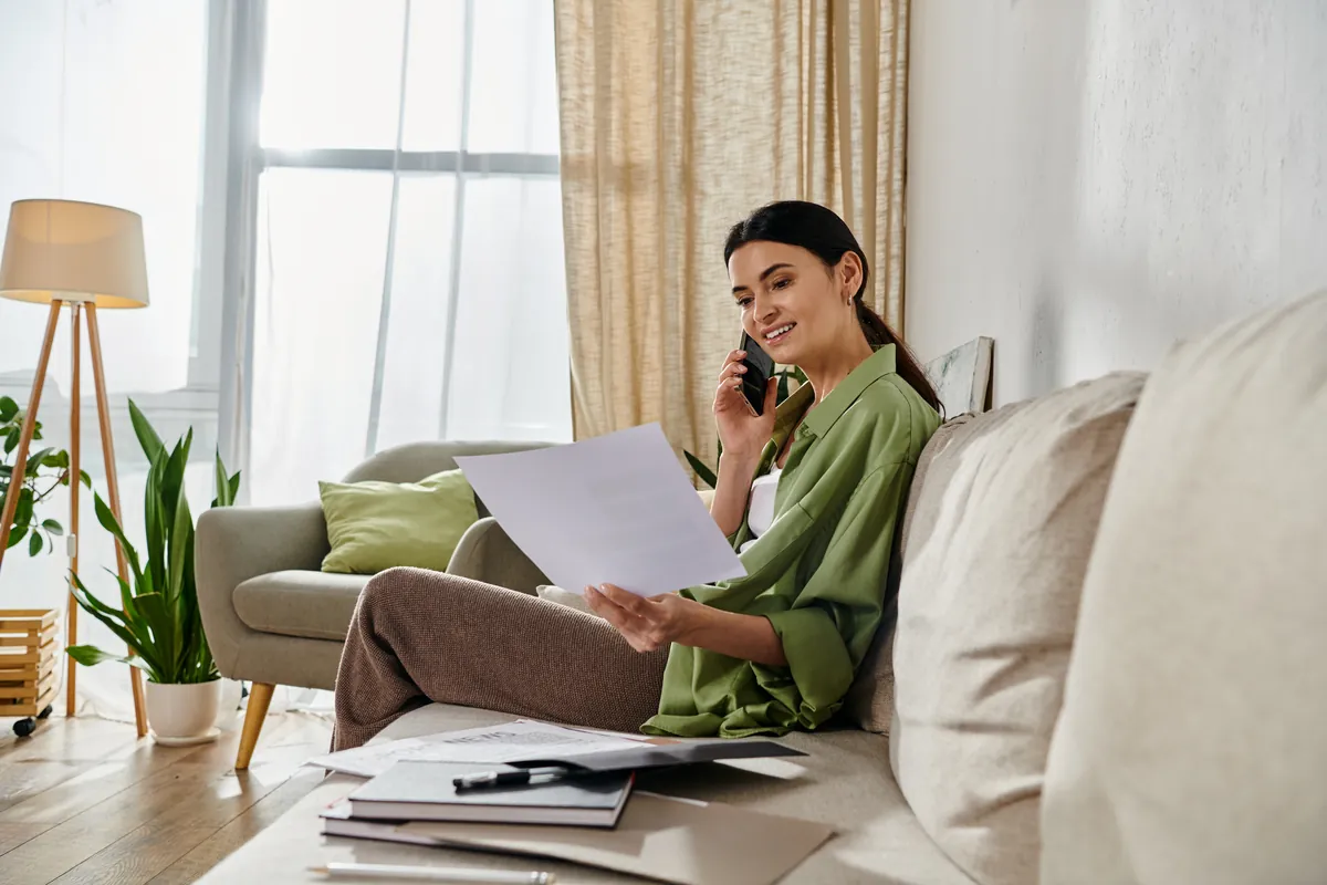 Femme examinant un document chez elle devant son ordinateur