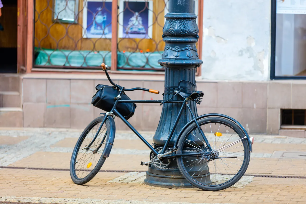 Vélo rétro garé contre un poteau dans une rue