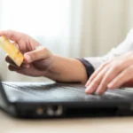 Mains tenant une carte de crédit pour un achat en ligne sur ordinateur