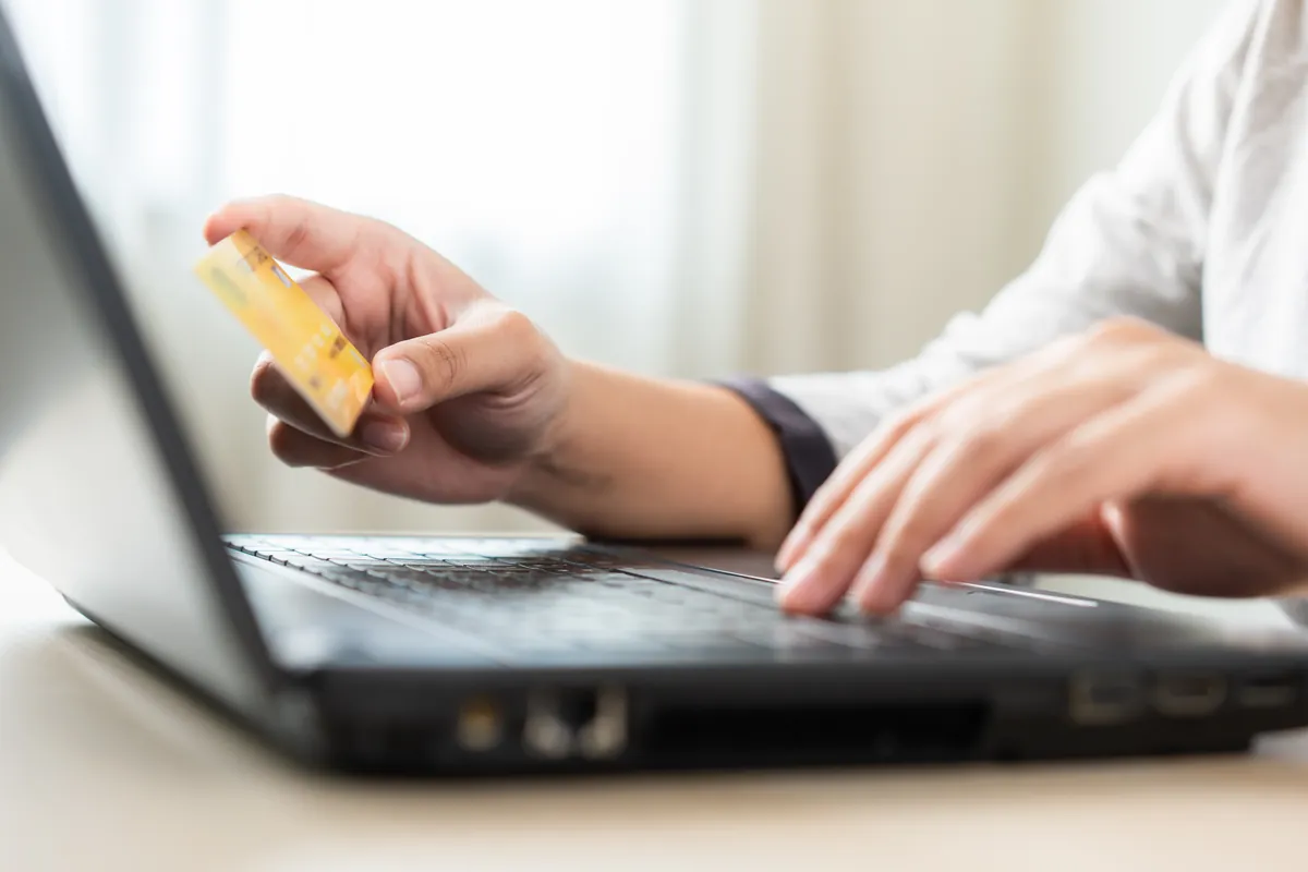 Mains tenant une carte de crédit pour un achat en ligne sur ordinateur