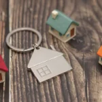 Clé et maisons miniatures posées sur du bois, projet immobilier