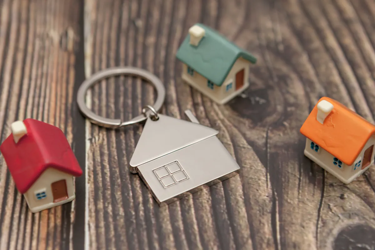 Clé et maisons miniatures posées sur du bois, projet immobilier