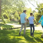 Famille se promenant main dans la main dans un parc ensoleillé