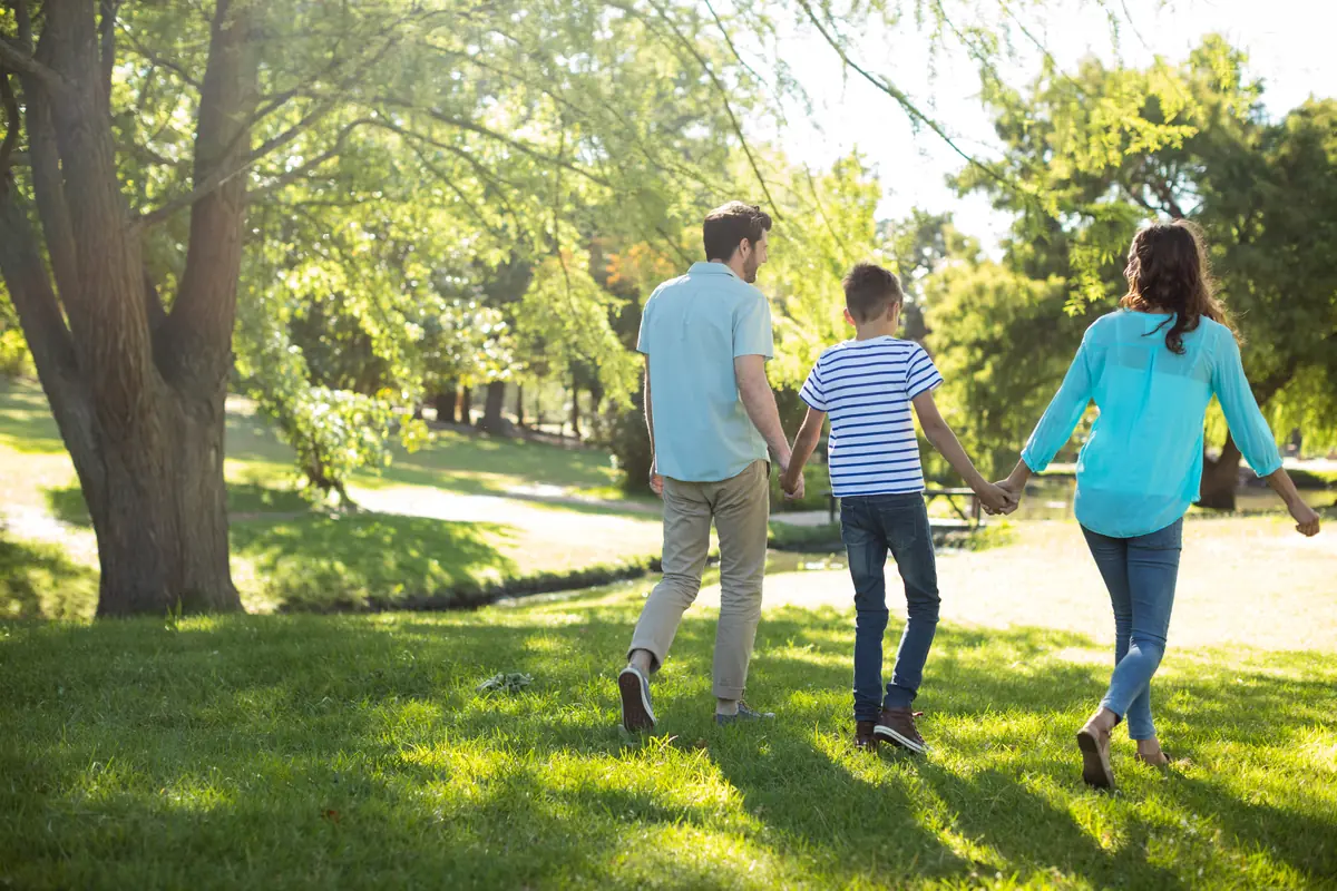 Famille se promenant main dans la main dans un parc ensoleillé