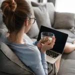 Femme sur son canapé faisant une demande de crédit en ligne sur son ordinateur