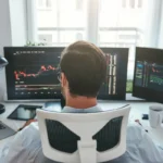 Trader devant plusieurs écrans de cotations boursières