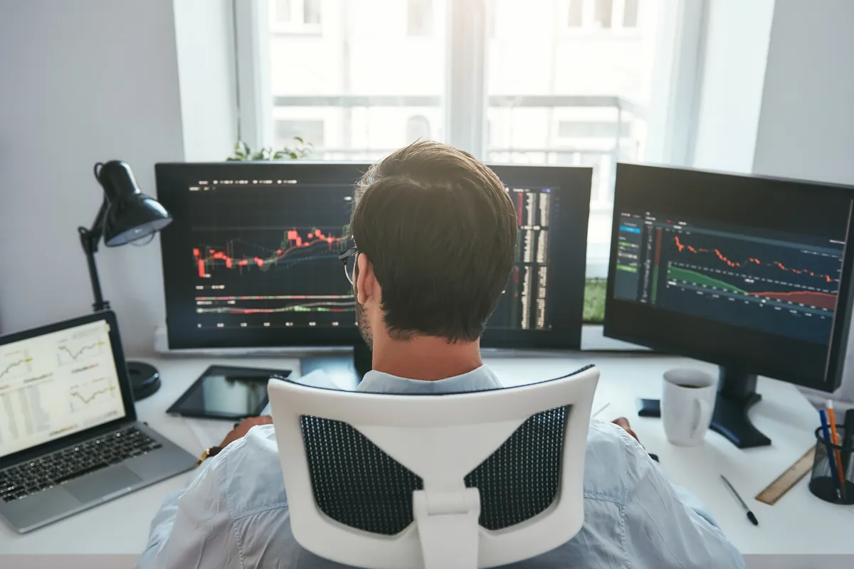 Trader devant plusieurs écrans de cotations boursières
