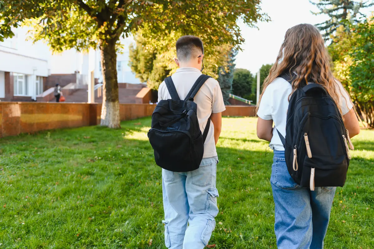 Deux élèves avec leur sac à dos marchant vers l'école