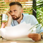 Homme pensif hésitant devant des documents de prêt