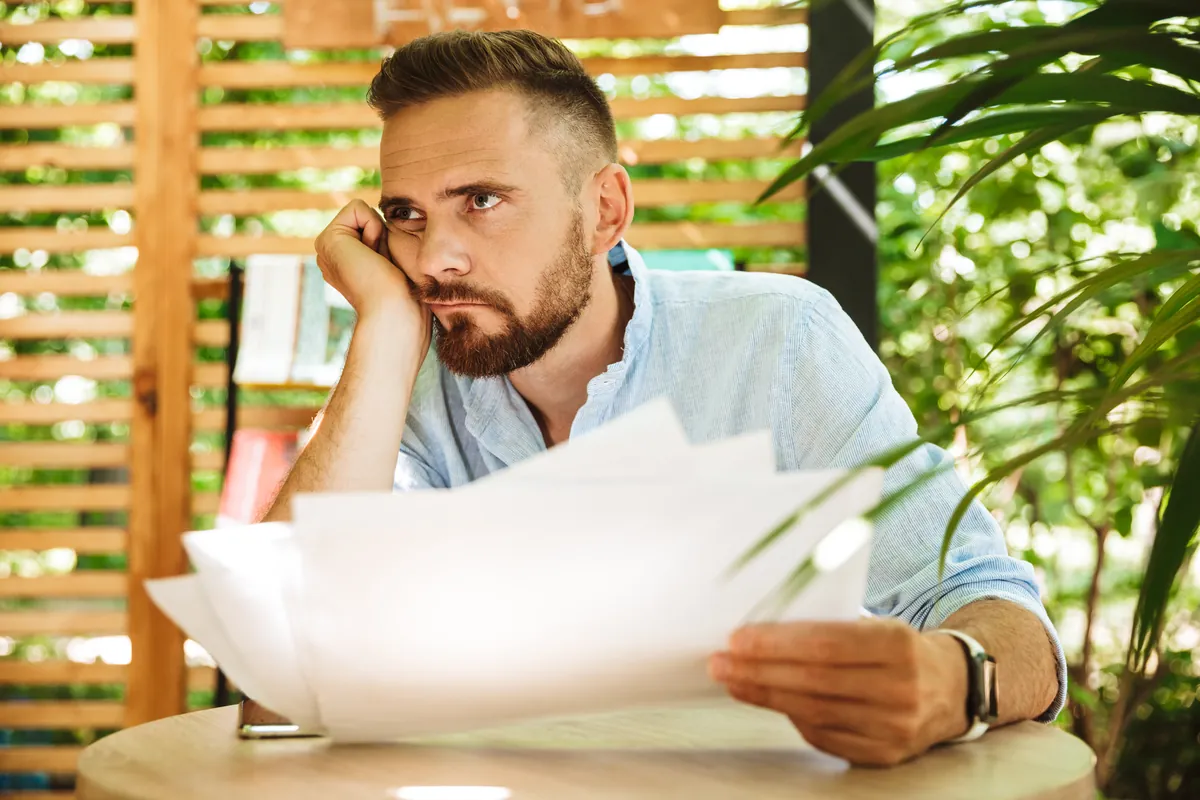 Homme pensif hésitant devant des documents de prêt