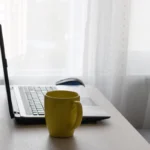Ordinateur portable et tasse jaune sur un bureau à la maison