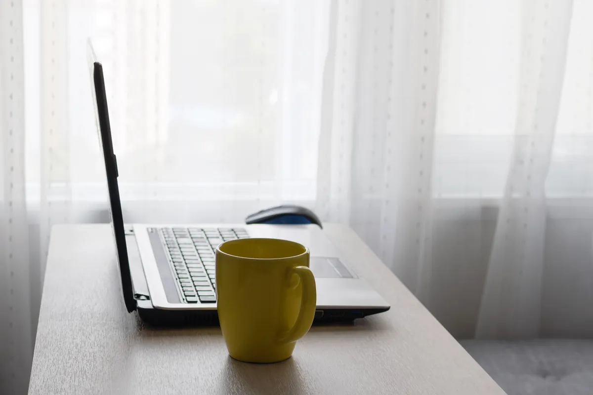 Ordinateur portable et tasse jaune sur un bureau à la maison