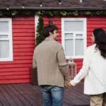Jeune couple main dans la main devant la maison qu'il souhaite acheter