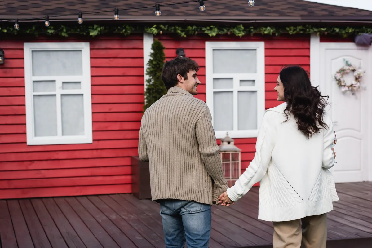 Jeune couple main dans la main devant la maison qu'il souhaite acheter