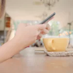Personne consultant son compte sur smartphone à la terrasse d'un café
