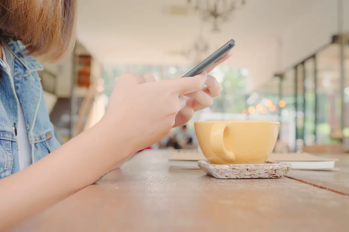 Personne consultant son compte sur smartphone à la terrasse d'un café