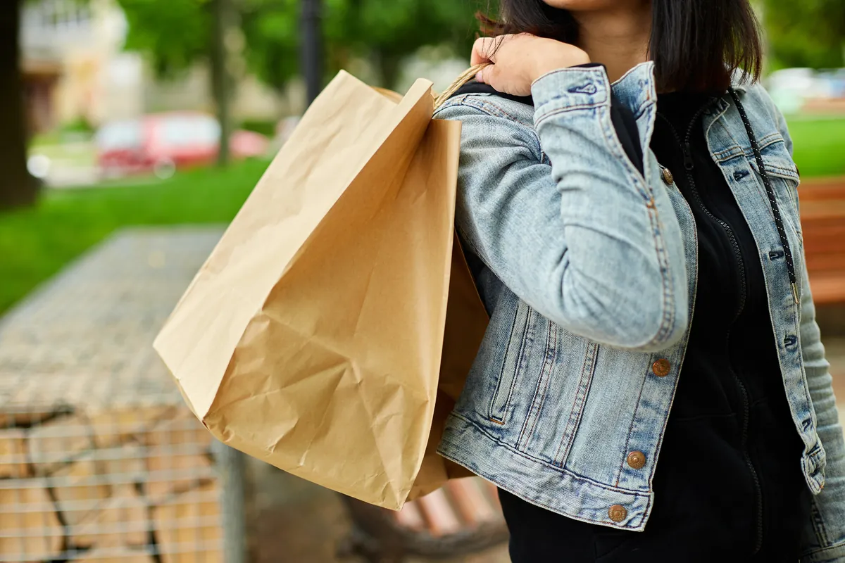 Femme portant des sacs de courses en papier dans la rue