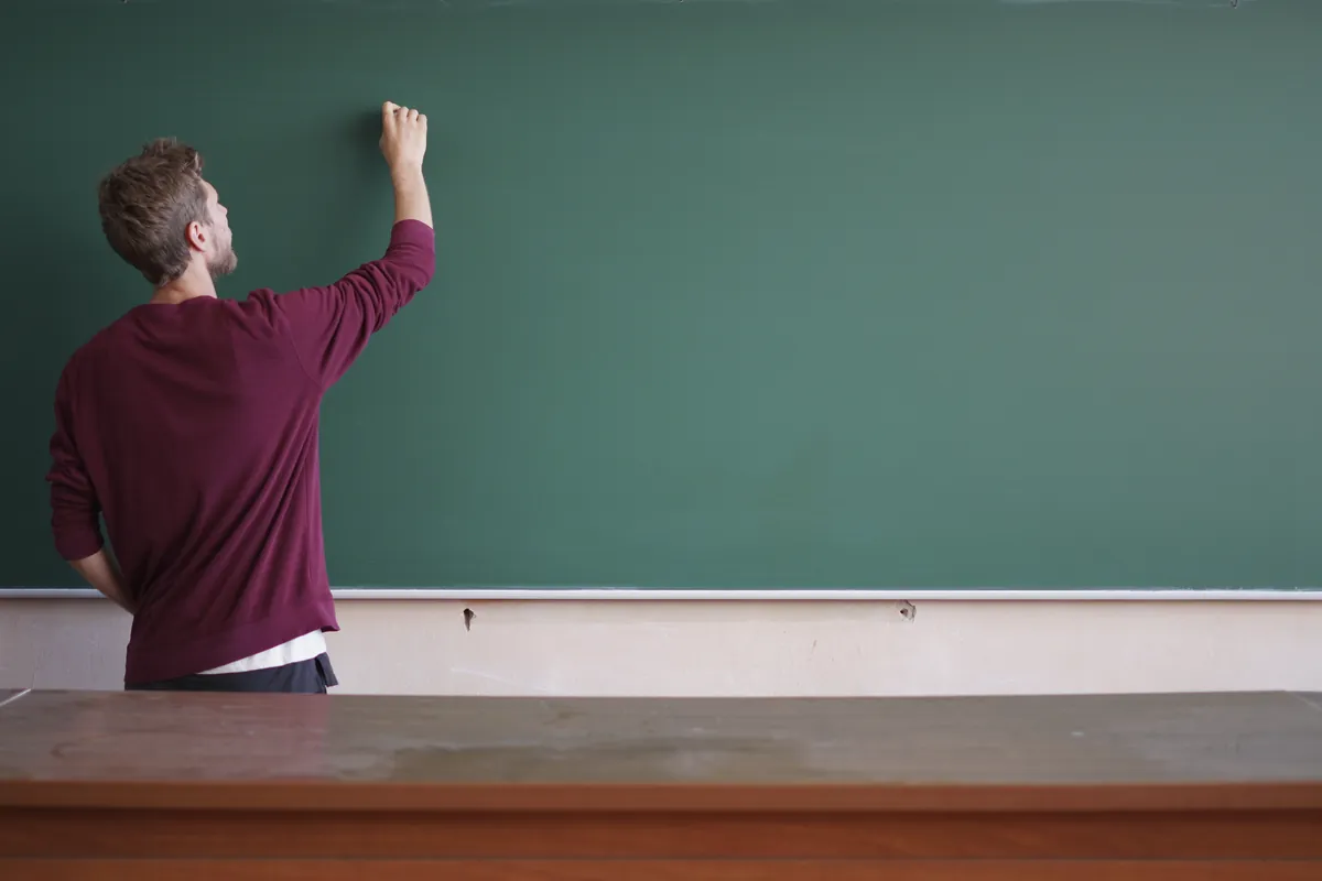 Enseignant écrivant au tableau noir dans une salle de classe
