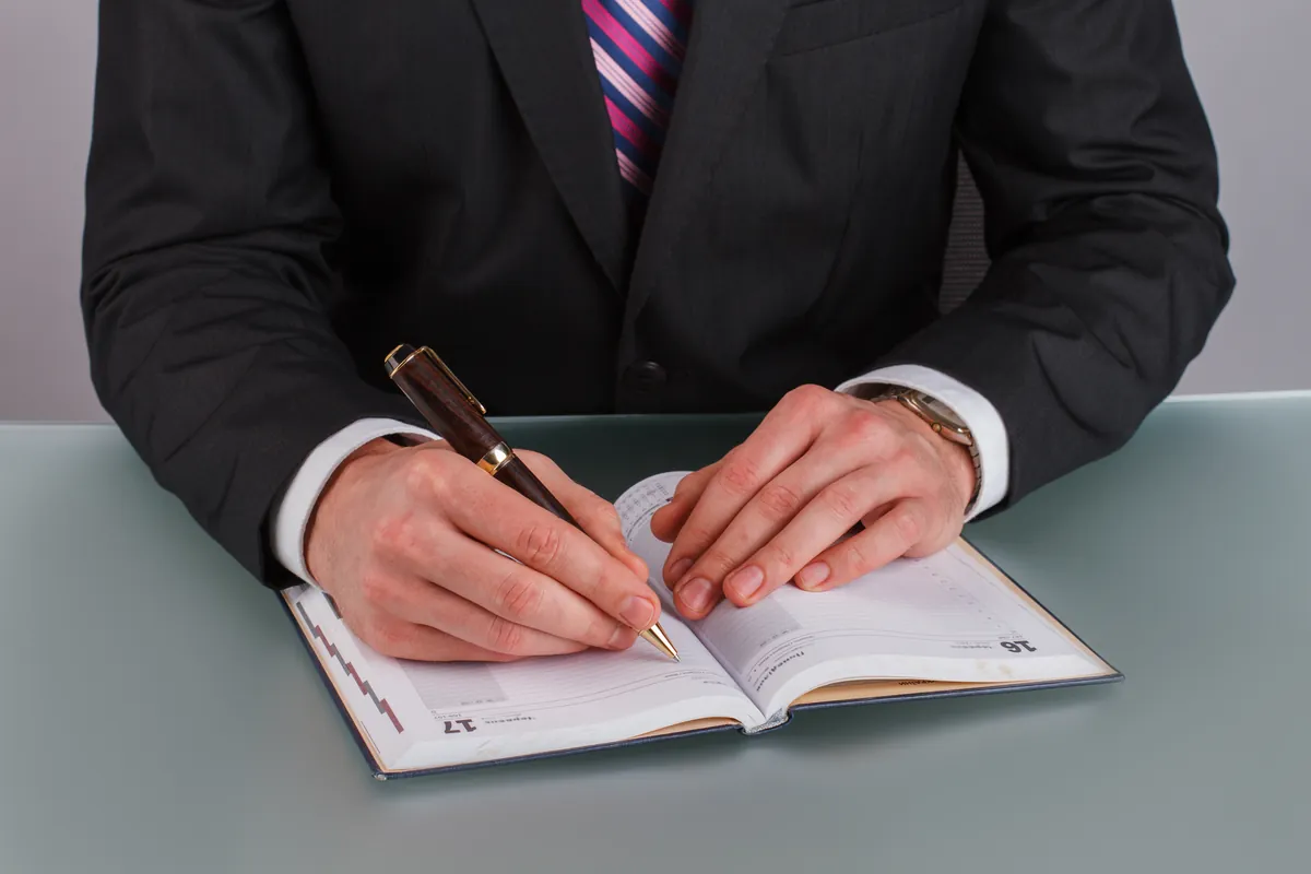 Mains notant des informations bancaires dans un agenda